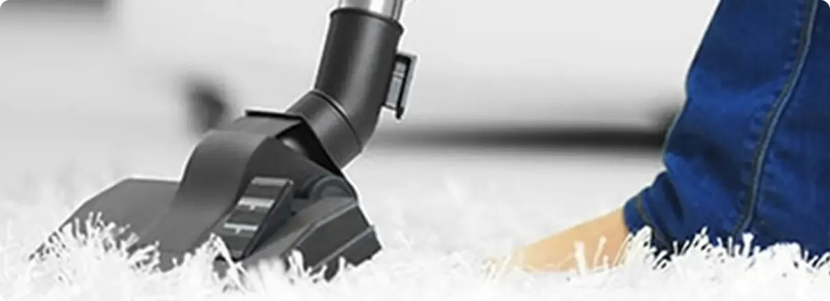 Close-up of a professional vacuuming a white carpet in Cos Cob.